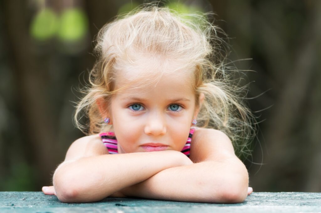 Child with arms crossed looking at camera