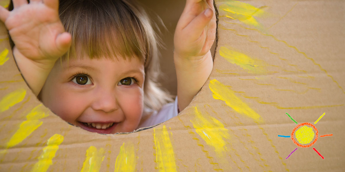 Child playing with sun cardboard box